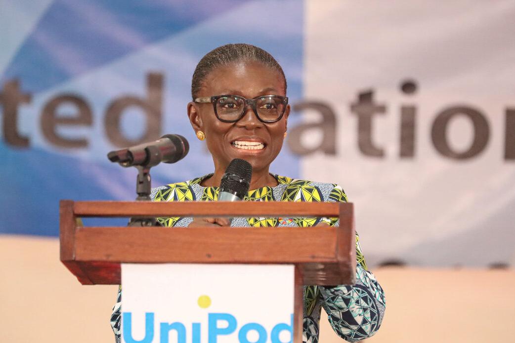 OiC SRSG Anita Kiki Gbeho speaking at a podium with a microphone during a United Nations event, with a banner in the background