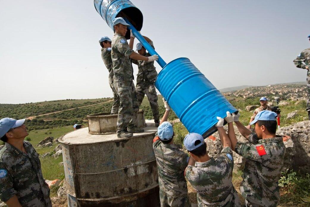 UN Peacekeepers lift equipment outdoors.